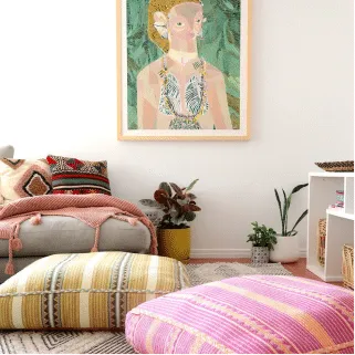 Living room with patterned floor cushions, a woven ottoman and a portrait artwork