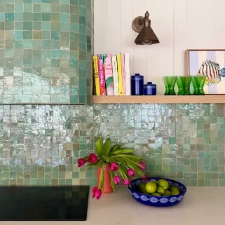 Close-up of a green zellige splashback with tulips and limes in a patterned bowl