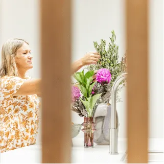 Sara Cornish arranging flowers in a kitchen, framed by timber battens