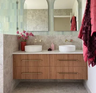 Timber double vanity with marble-look tiles, twin basins and pink flowers