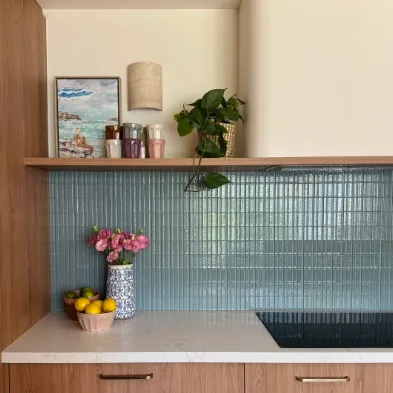 Kitchen with blue glass tile splashback, timber shelf and styled accessories