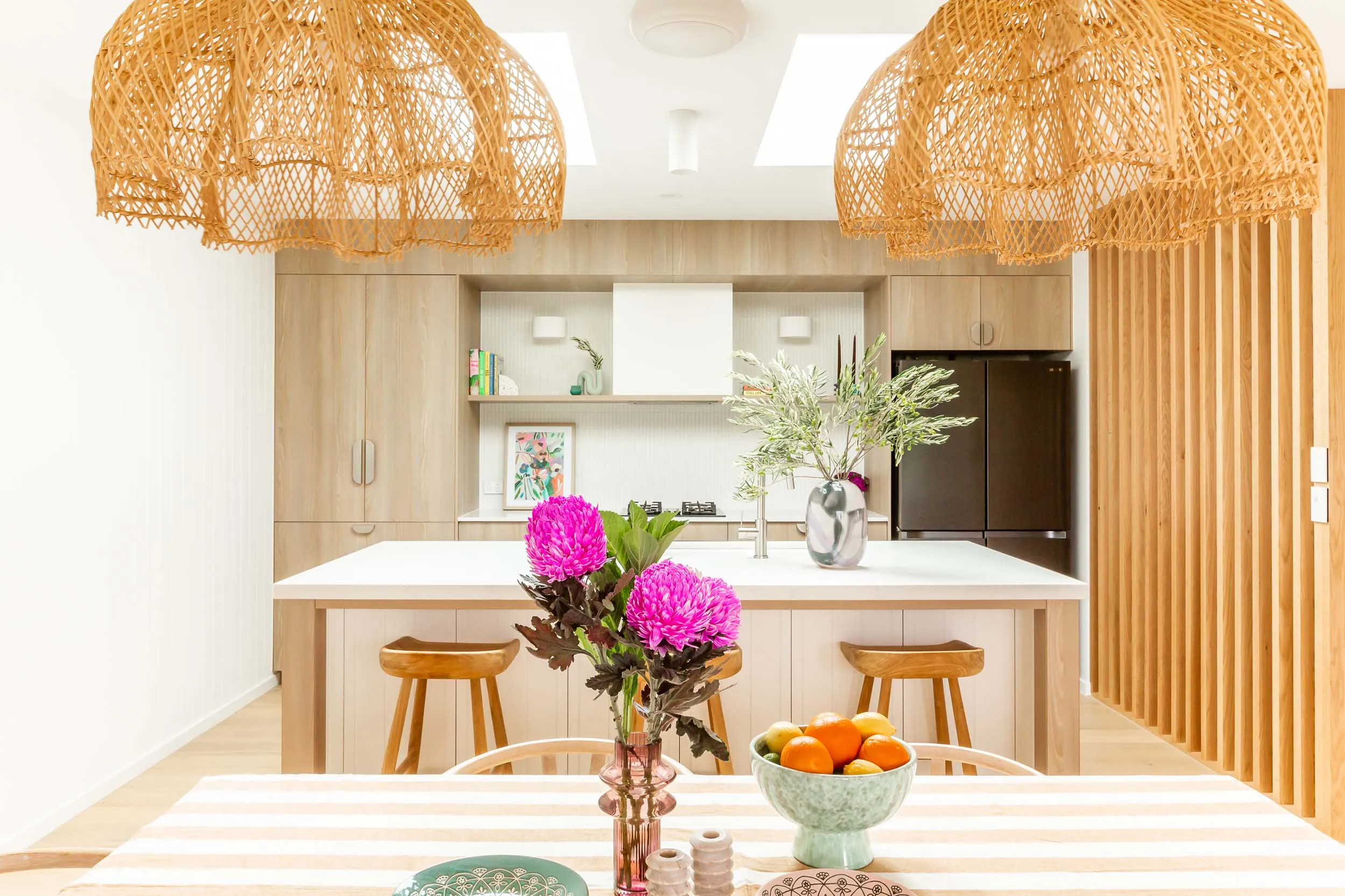Kitchen with timber cabinetry, rattan pendants and an island bench